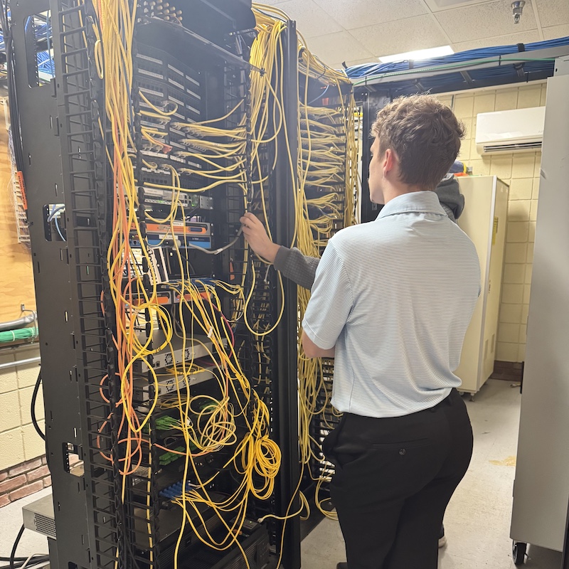 Brayden T. Tech Brayden looking at at computer network wiring